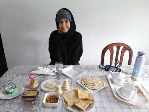 努沃勒埃利耶Nuwara eliya mountain view homestay的坐在桌子上,吃着食物的女人