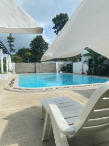 苏梅岛Chaweng Residence的游泳池旁的白色椅子和遮阳伞