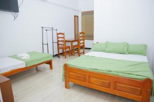 贾夫纳Amis Hotel & Restaurant的一间卧室配有两张床和一张桌子及椅子