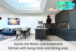 腓特烈港Auszeit Apartment SUNSHINE am Uferpark - nur 100 m bis zum Bodensee, direkt am Bodenseeradweg, 2 Schlafzimmer, 2 sonnige Dachterrassen, schnelles WLAN, kostenloser Tiefgaragenstellplatz, für bis zu 4 Personen的厨房设有客厅和用餐区。