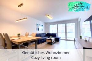 腓特烈港Auszeit Apartment SMILE am Uferpark - nur 100 m bis zum Bodensee, direkt am Bodenseeradweg, 2 Schlafzimmer, 2 Sonnenbalkone, schnelles WLAN, kostenloser Tiefgaragenstellplatz, für bis zu 4 Personen的客厅配有桌子和蓝色沙发