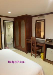 芭东海滩丹戎旅馆的一间带一张床和一张书桌的卧室以及一间浴室。