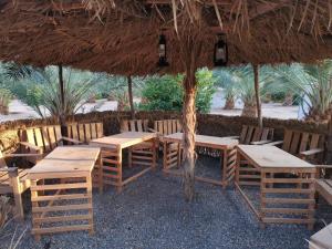 欧拉Almazham camp resort的餐厅设有一张带木桌和椅子的稻草伞下