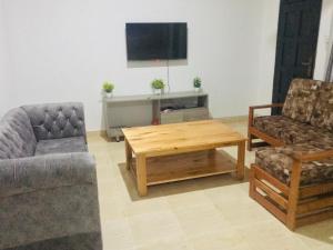 姆特瓦帕Hyven's Apartments的客厅配有两把椅子、一张桌子和一台电视