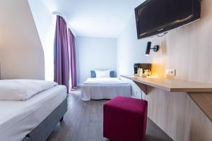 霍根海姆Taste Hotel Hockenheim的酒店客房设有两张床和一台平面电视。