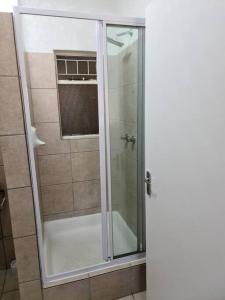 约翰内斯堡Cosy apartment with secure parking的浴室里设有玻璃门淋浴
