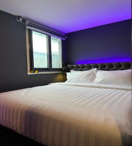 新加坡HOTEL JJH - newly opened near BUGIS的卧室配有白色床和紫色天花板