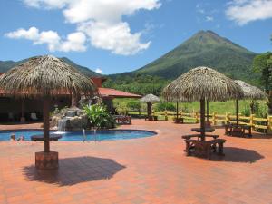 福尔图纳拉普拉德拉德尔阿雷纳尔酒店的一个带桌子和稻草遮阳伞的游泳池的度假酒店