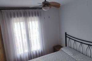 埃尔阿雷纳尔El casillo的一间卧室配有一张带吊扇和窗户的床。