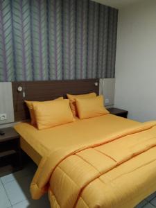 当格浪SMART Dream Inn的卧室内的一张带黄色床单和枕头的床
