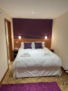 斯特利特The King Alfred的卧室配有一张带紫色枕头的大型白色床。