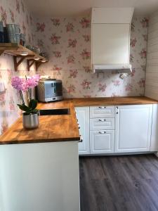 BroAnnehill i Bro的厨房配有白色橱柜和粉红色花卉壁纸