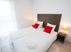 梅里尼亚克All Suites Appart Hôtel Bordeaux Mérignac - Aéroport的两张床铺,带两个红色枕头