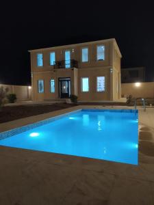 巴库Mardakan Villa的一座大型游泳池,在晚上在房子前面