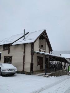 布克维Palaga Bukovel的一座雪覆盖的房子,前面有一辆汽车停放