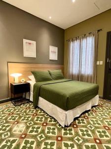 亚松森Lola’s home的一间卧室配有一张带绿色棉被的床