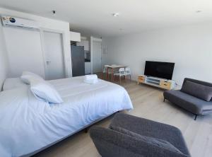 埃斯特角城SYRAH Premium B2 - Piscina privada con vista al mar by depptö的一间卧室配有一张床、一把椅子和电视。