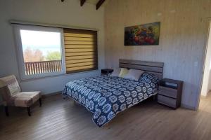 延基韦Cabaña frente al Lago Llanquihue的卧室配有床、椅子和窗户。