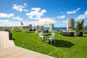 塔穆宁景湾关岛酒店的配有桌椅和雨伞的草坪