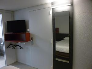马耶讷Brit Hotel Mayenne的一张床铺和一台电视机的镜子