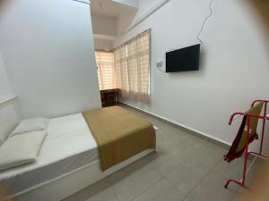 瓜拉丁加奴Roomstay Gemilang的一间卧室配有一张床和一台平面电视