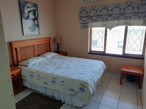 乌旺戈海滩Uvongo square Unit 24的一间卧室配有一张蓝色棉被和两个窗户。