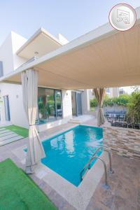 迪拜5 bedroom Villa - Dubai Hills的一座带遮阳伞的别墅内的游泳池