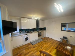 拉格斯cosy 1 bed flat Largs的厨房铺有木地板,配有白色橱柜。