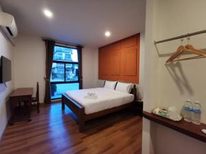 那空拍侬府โรงแรมรชาโขง Racha Khong Hotel的一间卧室配有一张床、一张书桌和一个窗户。