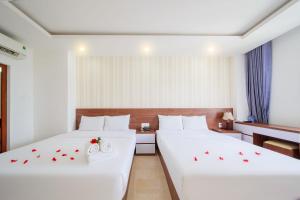 芽庄Ha Nhung Hotel Nha Trang的两张床铺,位于酒店房间,上面有玫瑰花