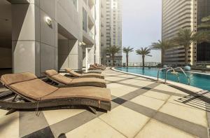 迪拜Maison Privee - High-Floor Trendy Apt with Marina, Palm & Ocean Vws的一座带躺椅的游泳池位于大楼旁