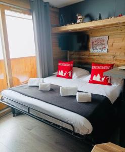 美贝尔Chalet Olympie, Appartement avec balcon et vue montagne, ski aux pieds, Méribel-Mottaret的一间卧室配有一张带红色枕头的大床