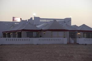 Qasr Al FarafirahShahrazad Camp in white desert, Egypt的白色的建筑,有一排屋顶