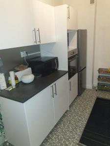 圣路易LOVE Appartement partagé avec le proprietaire的厨房配有白色橱柜和黑色冰箱。