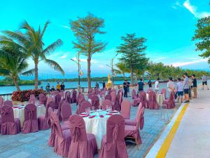 归仁Pearl Beach Hotel Quy Nhon的海滩上的餐厅设有粉红色的椅子和桌子