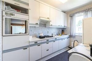 安特卫普SUPERB FLAT WITH 3 BEDROOMS PARKING AND BALCONy的厨房配有白色橱柜和炉灶烤箱。