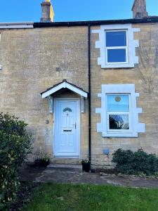 巴斯Rush Hill Cottage - with parking for 2 cars的一座带蓝色门和两扇窗户的房子
