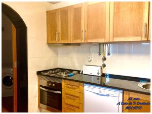 梅利迪什A Casa da Ti Deolinda的厨房配有木制橱柜和炉灶烤箱。