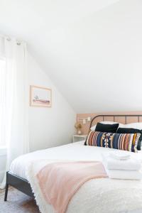 皮克顿Downtown Picton 2-Bedroom Boho Suite!的一间卧室配有一张带白色床单的床和一扇窗户。