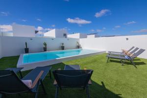 拉奥利瓦Villa Casilla de Costa Private Pool Luxury La Oliva By Holidays Home的一座带椅子的庭院和一座位于大楼内的游泳池