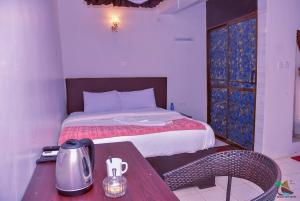 基苏木Beach View Hotel - Kisumu的一间卧室配有一张床、一张桌子和茶壶