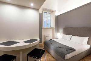 帕尔马Palazzo Liberati Apartments的一间卧室配有一张床、一张桌子和一个窗户。