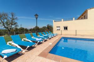 LlambillasCan Bugantó amplia casa con piscina y jardín的游泳池旁的一排蓝色椅子