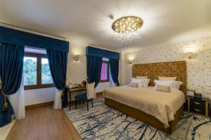 辛特拉Sintra Marmòris Camélia的一间卧室配有一张带蓝色窗帘和吊灯的床。