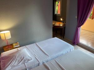 Matoury拉查米耶尔酒店的一间卧室设有两张床、一张桌子和一个窗口