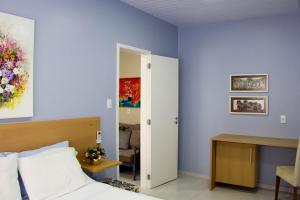 弗洛里亚诺波利斯Solar da Lorena的一间卧室设有蓝色的墙壁、一张床和一张书桌