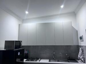 比勒陀利亚Beevap Guesthouse的一间带白色橱柜和水槽的厨房以及一台电视。