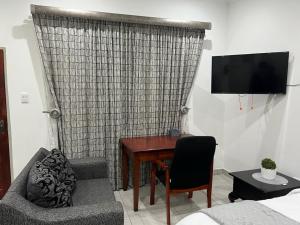 比勒陀利亚Beevap Guesthouse的客厅配有书桌、沙发和电视