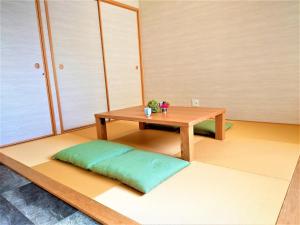 京都GLANZ KEI Kyoto Station的一间房间,地板上设有一张桌子和一个绿色枕头