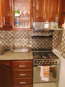 利马Departamentos Las Lilas Surco Lima的厨房配有木制橱柜和炉灶烤箱。